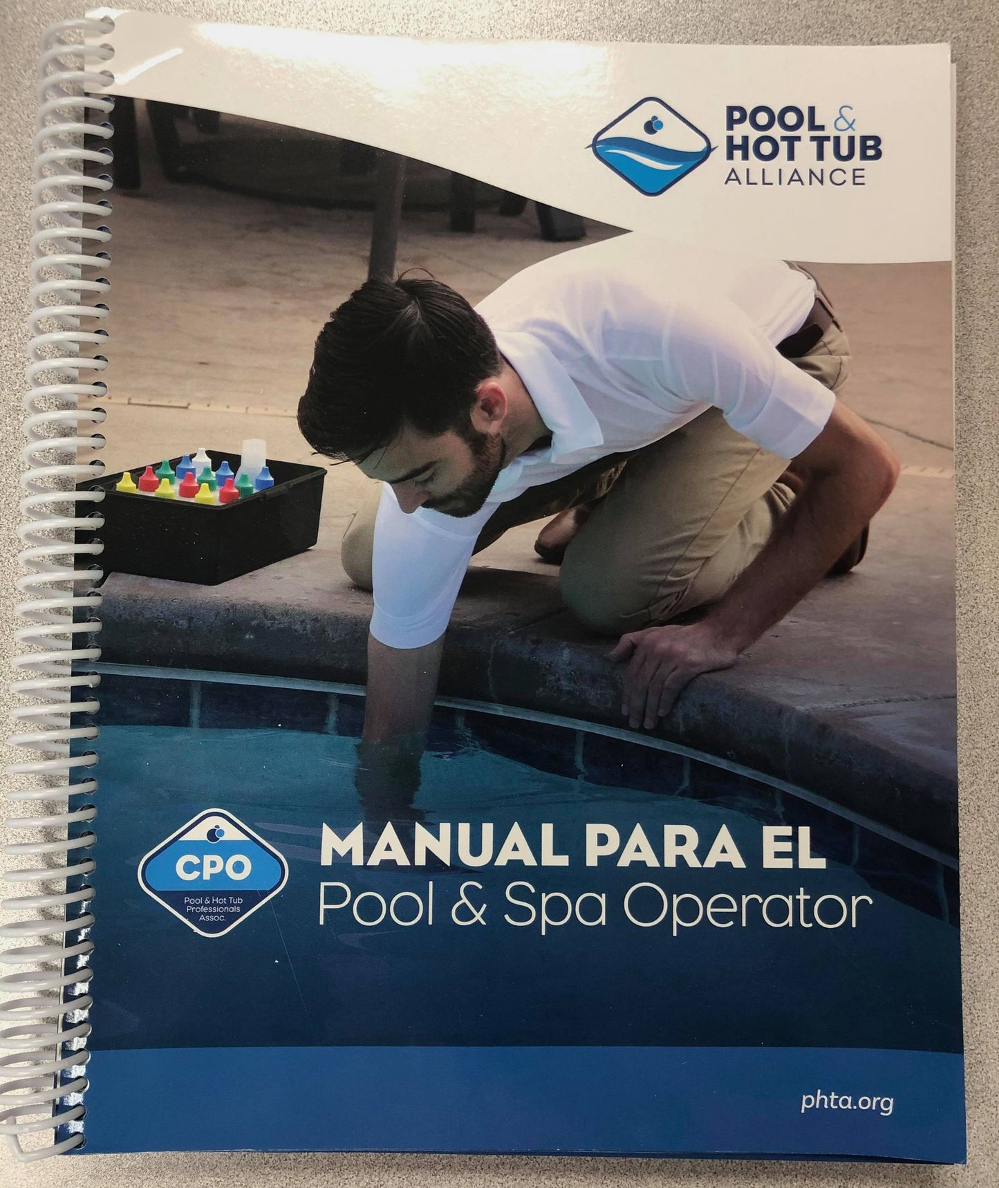 Certified Pool and Spa Operator handbook in Spanish with Pool & Hot Tub Alliance logo and man testing pool water