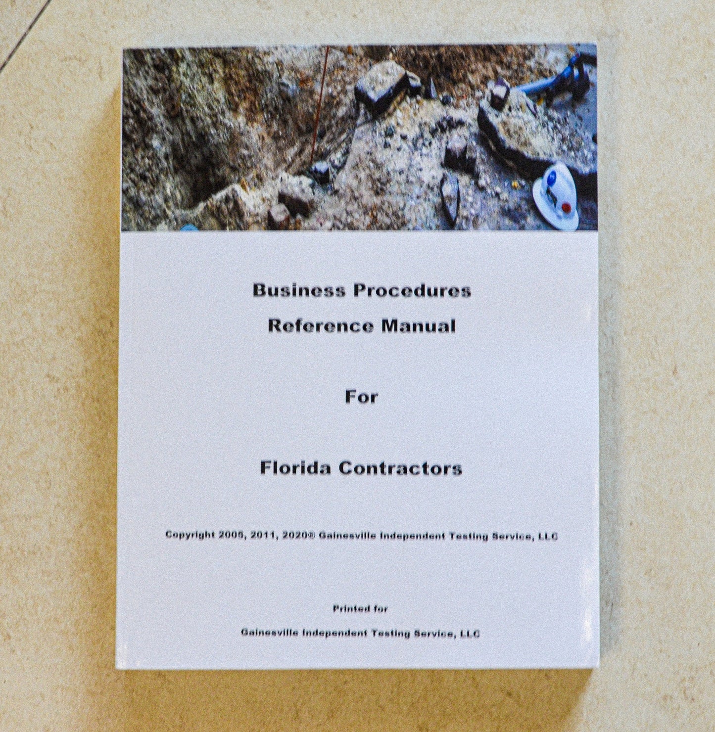 Business Procedures Reference Manual cover with construction site dirt, rocks, and safety helmet on beige background