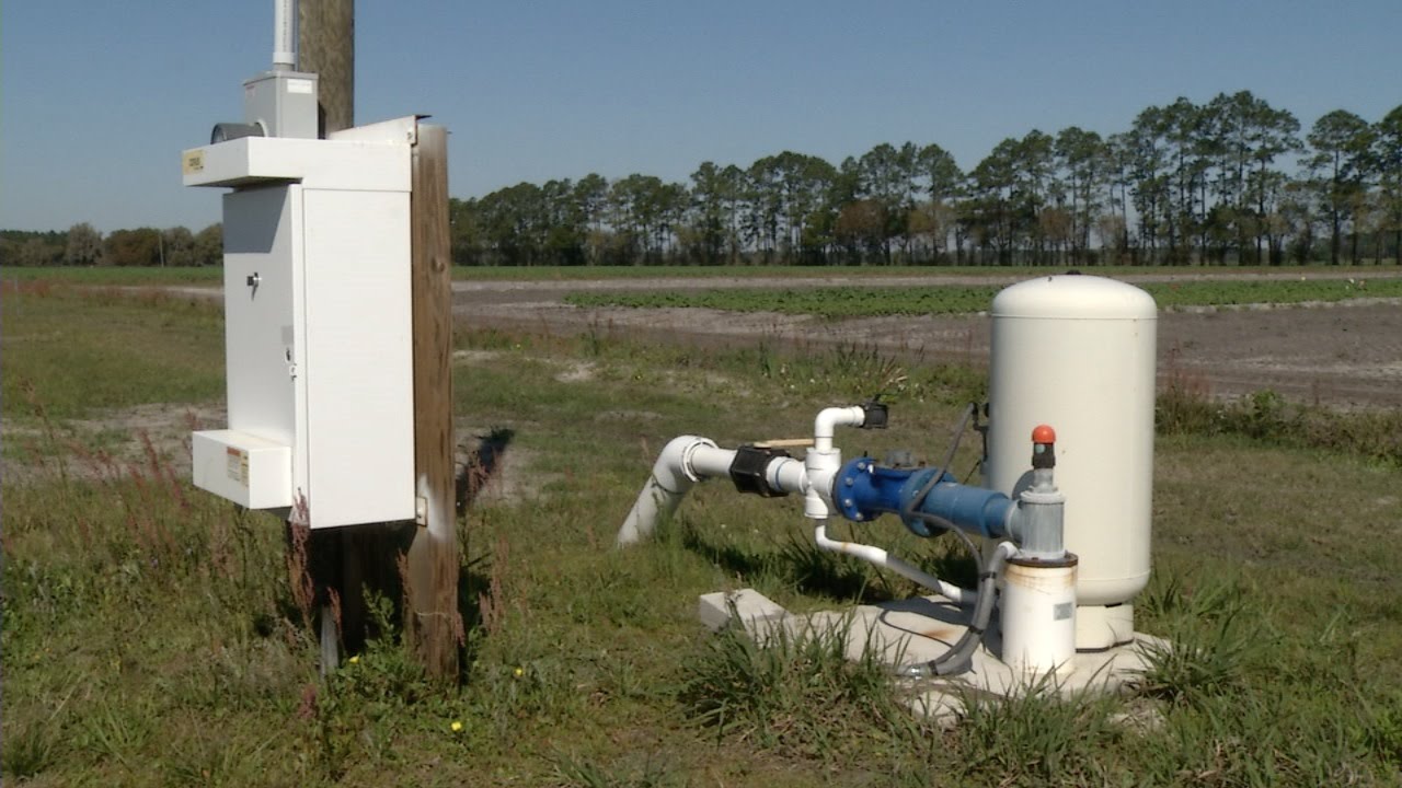 Irrigation system control panel and pump setup in a field with trees in the background on a clear day