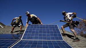 Workers installing solar panels on rooftop with safety harnesses for solar contractor training course promotion