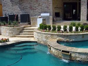 Residential backyard pool with stone retaining walls, landscaped garden, and steps leading to a covered patio area