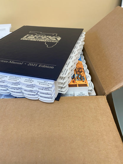 Stack of professionally tabbed 2021 Contractors Manual with visible highlight tabs inside open cardboard box